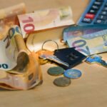 Euro banknotes and coins with house keys on a table symbolize finance and real estate.